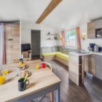 Intérieur avec table coin salon et kitchenette du mobil-home Pause à Litteau