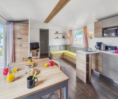 Intérieur avec table coin salon et kitchenette du mobil-home Pause à Litteau