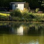 Bord d'étang avec mobil-home et reflet au Pleasant Shepherd Hut