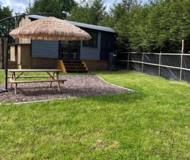 Pelouse avec table de pique-nique et parasol devant la cabane du berger au Pleasant Shepherd Hut