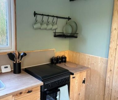 Intérieur coin cuisine en bois avec cuisinière tasses et vaisselle dans la Pleasant Shepherd Hut