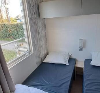 Chambre avec deux lits simples et fenêtre donnant sur le jardin au camping Plouescat