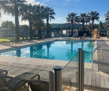 Piscine extérieure bordée de palmiers au camping Premium Mobilhome Grimaud