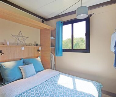 Chambre avec lit double et fenêtre donnant sur la nature au camping RAS L'BOL