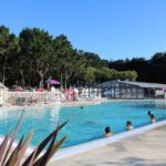 Piscine extérieure avec baigneurs et terrasse au camping RESPIRE