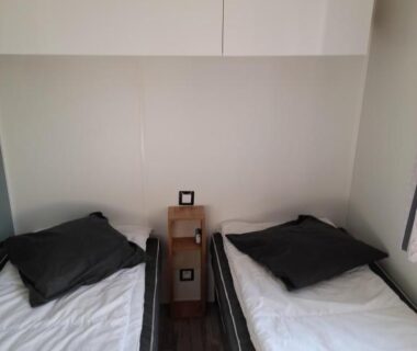 Chambre avec deux lits simples et table de chevet au RIVA BELLA Lodge 171