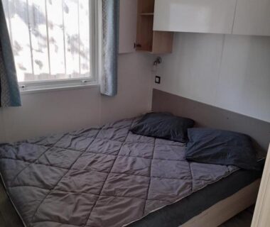 Chambre avec lit double oreillers et fenêtre dans le RIVA BELLA Lodge 171
