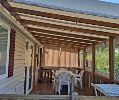 Terrasse couverte avec table et chaises sur mobil-home au camping Repos mérité