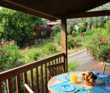 Terrasse couverte avec table dressée et jardin à la Résidence Lagrange Vacances Les Cottages Varois