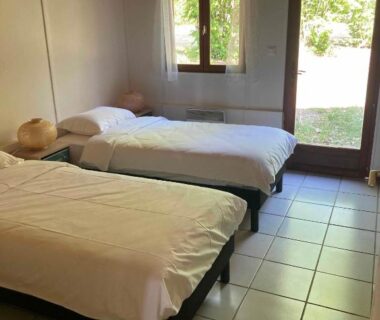 Chambre avec deux lits et porte-fenêtre dans la Résidence les chênes