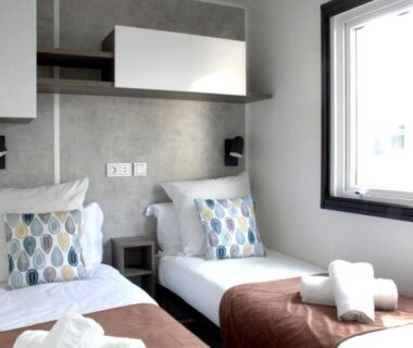 Chambre avec deux lits simples, coussins et serviettes dans le bungalow Réveillez la Belle au Bois Dormant