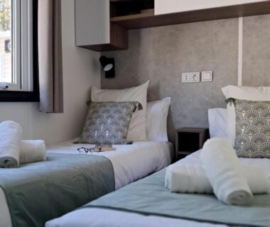 Chambre intérieure avec deux lits et serviettes dans le bungalow Réveillez la Belle au Bois Dormant