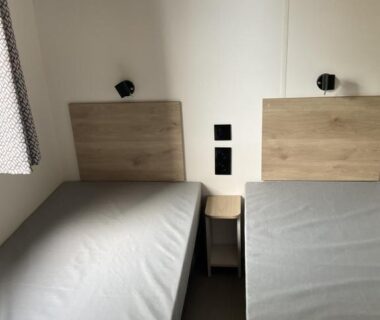 Chambre avec deux lits simples et table de nuit au camping Rêves de pins