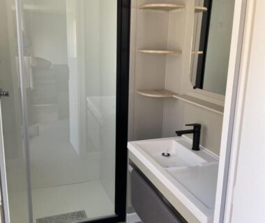 Salle de bain avec douche vitrée et lavabo au camping Rêves de pins