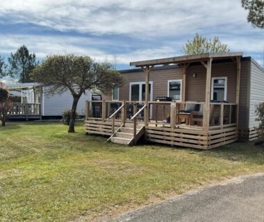 Terrasse en bois et pelouse devant mobil home au camping Rêves de pins