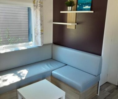 Coin salon avec banquette et petite table dans le mobil-home Riva Bella chez Caraphou