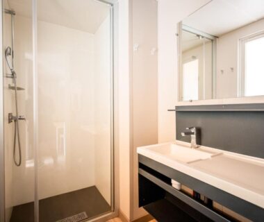 Salle de bain avec douche et lavabo au camping Rives d'Arc