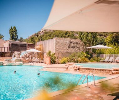 Piscine extérieure avec parasols et transats au camping Rives d'Arc