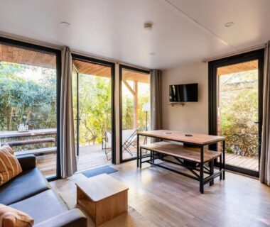 Salon lumineux avec baie vitrée donnant sur terrasse au camping Rives d'Arc