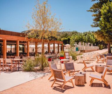 Terrasse extérieure avec chaises en bois et tables au camping Rives d'Arc