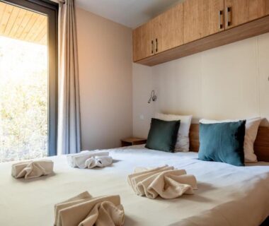 Chambre avec lit double coussins et serviettes pliées au camping Rives d'Arc