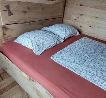 Intérieur en bois avec lit double dans la roulotte Le Coq La Mazille