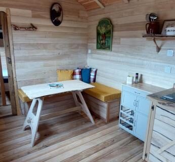 Intérieur de roulotte avec coin repas et kitchenette dans la Roulotte Le Coq La Mazille