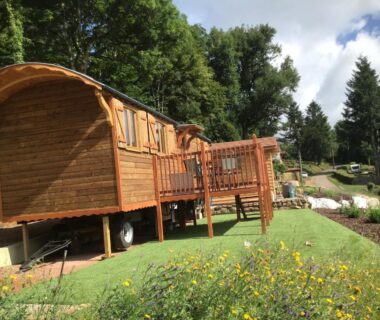 Terrasse en bois devant roulotte sur pelouse à la Roulotte Le Coq La Mazille