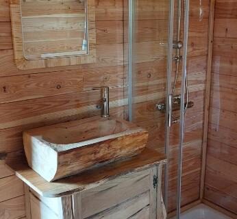 Salle d'eau en bois avec lavabo et cabine de douche dans la Roulotte Le Coq La Mazille