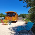 Terrasse extérieure avec chaises colorées et transat de la Roulotte à Sapharey