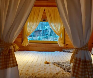Intérieur de roulotte avec lit et rideaux dans la Roulotte avec piscine la jonquille