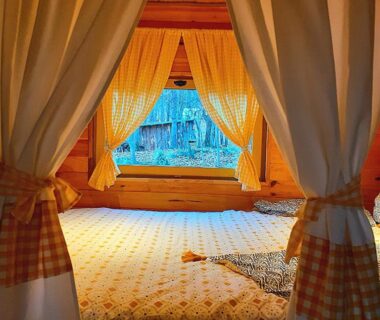 Intérieur de roulotte en bois avec lit et rideaux dans la Roulotte avec piscine la jonquille