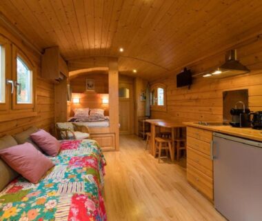 Intérieur en bois avec lit canapé et kitchenette dans la Roulotte de la Villa Font Vive