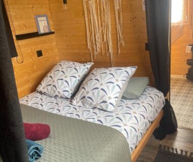 Intérieur en bois avec lit double et coussins dans la Roulotte hébergement atypique