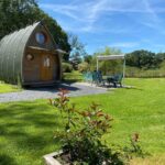 Pelouse avec roulotte en bois et coin repas extérieur aux Roulottes des Combrailles