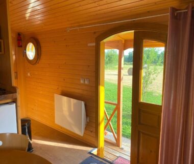 Intérieur de roulotte en bois avec porte ouverte sur pelouse aux Roulottes des Combrailles
