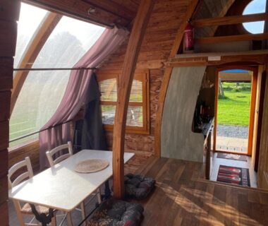 Intérieur de roulotte en bois avec table et chaises dans les Roulottes des Combrailles