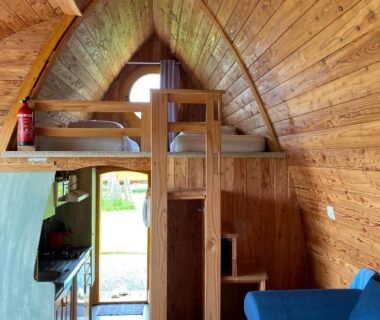 Intérieur de roulotte en bois avec mezzanine lits superposés canapé et climatisation aux Roulottes des Combrailles