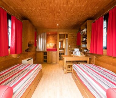 Intérieur en bois avec lits et kitchenette dans les Roulottes et Cabanes de Saint Cerice