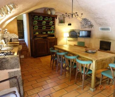 Salle à manger voûtée avec grande table et chaises dans les Roulottes et Cabanes de Saint Cerice