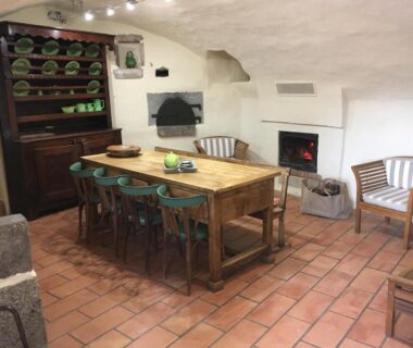 Intérieur salle à manger avec grande table en bois, vaisselier et cheminée dans les Roulottes et Cabanes de Saint Cerice