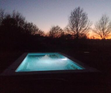 Piscine extérieure éclairée au crépuscule au SafariLodge 6 persoons