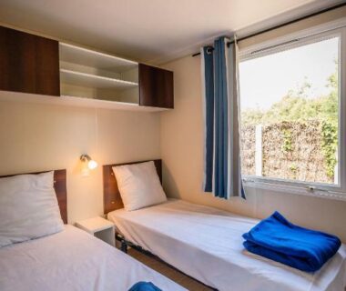 Chambre avec deux lits simples et fenêtre au camping Sauvage