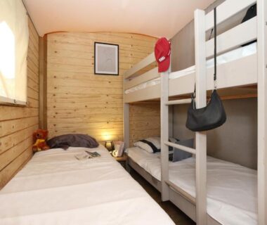Cabine en bois avec lits superposés et lit simple au Seasonova Camping Les 7 iles