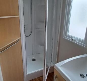 Intérieur salle d'eau avec cabine de douche et lavabo dans le Mobilhome 5P TV Séjour Normandie