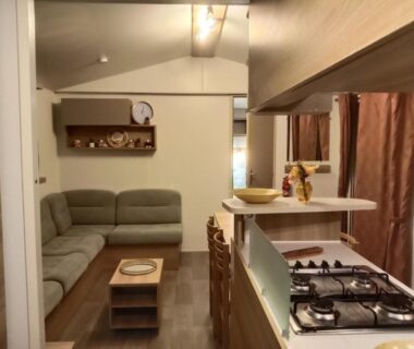 Coin salon avec canapé et kitchenette dans le mobile home LUMINOSA
