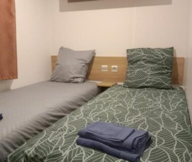 Chambre avec deux lits simples et serviettes pliées dans le mobile home LUMINOSA