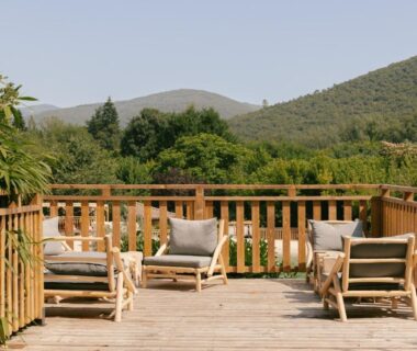 Terrasse en bois avec fauteuils et coussins donnant sur les collines du Slow Village Anduze - Cévennes
