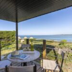 Terrasse couverte avec table et chaises face à la mer au Slow Village Breizh Légendes