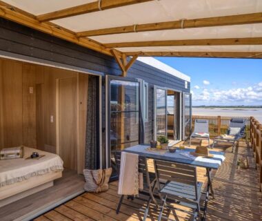 Terrasse en bois avec table et chaises et vue mer au Slow Village Breizh Légendes
